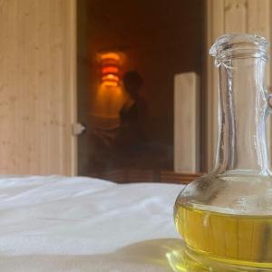 une bouteille de verre remplie de liquide jaune assise sur un lit dans l'établissement Cottage Spa Ada, à Ada