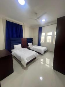 two beds in a room with blue curtains at RED-25 - Razat Alard 4 in Salalah