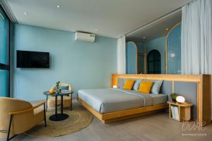 a bedroom with a bed with yellow pillows and a table at Bare Han - Bare Boutique Stays in Da Nang