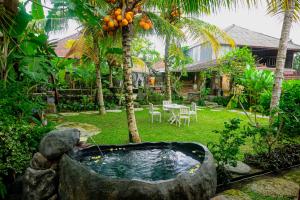 un jardín con bañera en un patio con palmeras en Kresna Asih House, en Tampaksiring