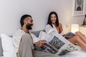 a man and woman sitting on a bed reading a newspaper at Palazzo Marzionna in Polignano a Mare
