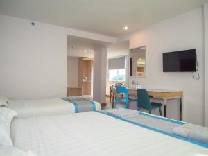 a hotel room with two beds and a desk and a television at TD Mutiara Hotel Semporna in Semporna