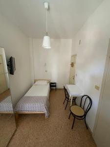 a room with two beds and a table and chairs at Hotel Naviglio in Marina di Pietrasanta