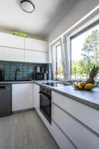 kuchnia z białymi szafkami i miską owoców na ladzie w obiekcie Dream Summer House Fonyód w mieście Fonyód