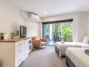 a bedroom with two beds and a television and a chair at Cosy Hotel Room with plunge pool at Kingscliff Salt Beach Resort and Spa in Kingscliff