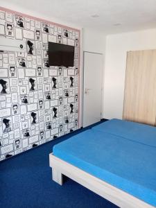 a bedroom with a blue bed and a wall with a tv at Manhattan Penzion in Písek