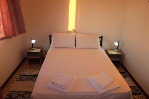 a bed in a small room with two lamps at Anastazia's Seaside Apartments in Roda