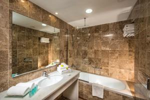 a bathroom with a sink, mirror, and bathtub at Annabelle Beach Resort in Hersonissos