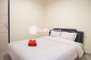 a pair of red shoes sitting on top of a bed at RedDoorz at Astana Malioboro in Yogyakarta +11 photos