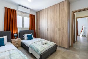 a bedroom with two beds and an orange curtain at Olive 2-Bedroom Apartment in Larnaca in Larnaka