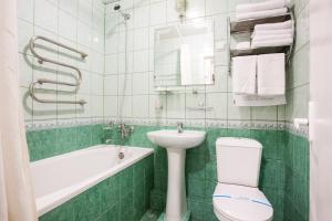 a bathroom with a toilet and a sink and a bath tub at Bukovyna Hotel in Chernivtsi