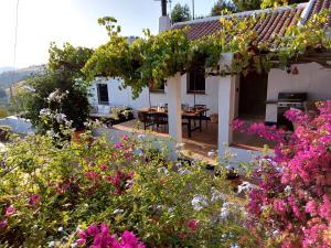 uma casa com um jardim com flores em frente em Finca El Sueño Andaluz em Villanueva de la Concepción