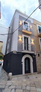 een wit gebouw met een zwarte deur en een balkon bij Just Here apartments - Lascia Fare a Dio in Bari