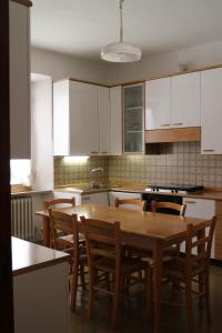 una cocina con armarios blancos y una mesa y sillas de madera. en Il piccolo casale 1950, en Fabriano