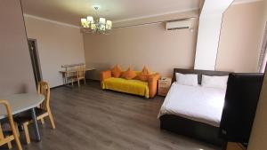 Un dormitorio con una cama, un sofá y una mesa. en Orange apartment with panoramic view, en Bishkek