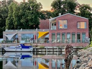 a red brick house with a boat on the water at Apt "Sunset Lounge" in Waase - Ummanz - Meerblick, Kamin, Sauna in Mursewiek