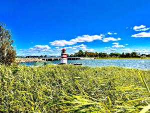 a lighthouse in the middle of a body of water at Apt "Sunset Lounge" in Waase - Ummanz - Meerblick, Kamin, Sauna in Mursewiek