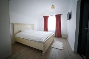 een slaapkamer met een bed en een raam met rode gordijnen bij Golden House Banffy in Topliţa