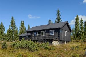 a black house sitting on top of a hill at Cottage right next to cross country tracks in Ringsaker