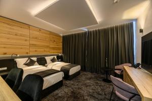 a hotel room with two beds and a television at B THE HOTEL in Sfântu-Gheorghe
