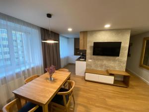 a living room with a dining table and a television at Jaukūs apartamentai in Telšiai