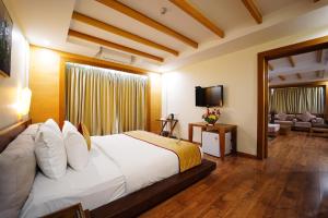 a bedroom with a large white bed and a television at Quality Inn VIHA in Kumbakonam