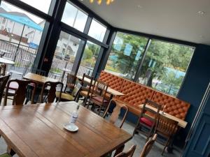 a restaurant with a wooden table and chairs and windows at Loch Lomond Hotel in Balloch