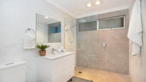 a white bathroom with a shower and a sink at Sutton Forest Retreat The Hideaway in Sutton Forest +17 photos