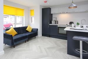 ein Wohnzimmer mit einem blauen Sofa und einer Küche in der Unterkunft No1 Luxury Service Apartments in Belfast