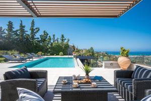 a patio with a pool and chairs and a table at Eunoia Villa Crete in Prasás