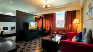 een woonkamer met een rode bank en een televisie bij Arman Hotel Juffair Mall in Manamah