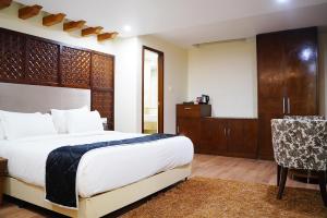 een slaapkamer met een bed, een tafel en een stoel bij Quality Inn VIHA in Kumbakonam