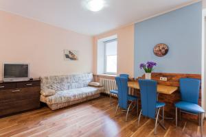 ein Wohnzimmer mit einem Tisch und blauen Stühlen in der Unterkunft Cozy apartments near Olympic Stadium in Kiew