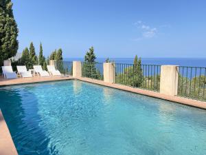 a swimming pool with chairs and the ocean in the background at Alconasser 2 - Amazing Seaviews between Deia & Soller in Sóller