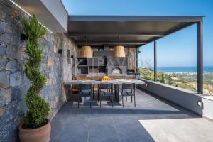 a patio with a table and chairs on a wall at Eunoia Villa Crete in Prasás