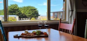 a table with two glasses of wine and a plate of food at Buln Buln Cabins in Yanakie