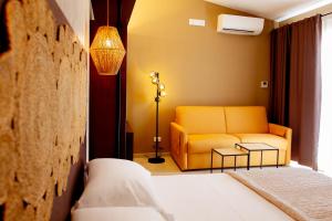 a living room with a yellow couch and a bed at Albergo Il Giardino in Rodi Garganico