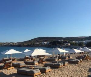 a beach with chairs and umbrellas and the water at Villa Ambelas - Traditional House in Ambelas