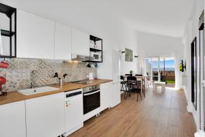 a kitchen with white cabinets and a dining room at Beautiful house with pool in Caleta De Fuste