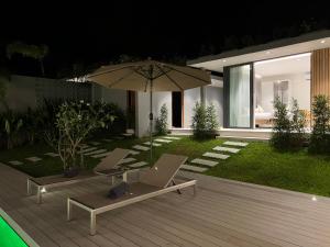 eine Terrasse mit einem Sonnenschirm, 2 Stühlen und einem Laptop in der Unterkunft AURA GARDEN 2, pool & garden villa, Choengmon 500m in Koh Samui 