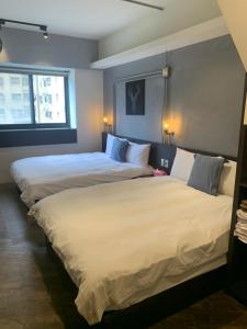 2 camas en una habitación de hotel con sábanas blancas en 一中自在居 en Taichung