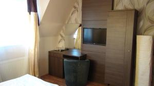 a bedroom with a tv and a desk and a bed at Penzion Vila Aria in Nitra