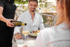 a man pouring a glass of wine for a woman at Bluesun Hotel Borak in Bol