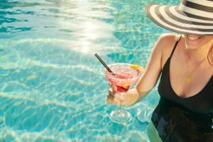 a woman in a hat holding a drink by a pool at Bluesun Hotel Borak in Bol