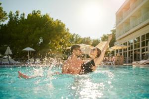 a man and woman sitting in a swimming pool at Bluesun Hotel Borak in Bol