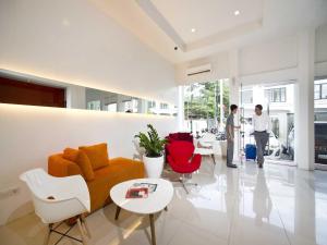 a living room with a couch and red chairs at Zuri Express Hotel Pekanbaru in Pekanbaru