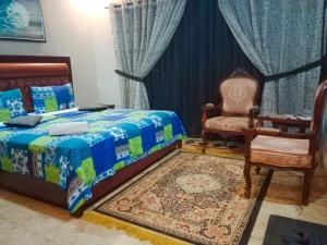 a bedroom with a bed and a chair at Seaview Lodge Guest House in Karachi