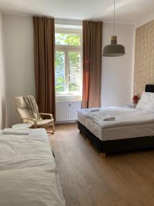 sypialnia z 2 łóżkami, krzesłem i oknem w obiekcie Žižkov tower suites w Pradze