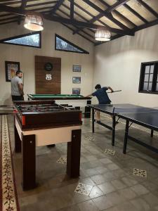 two people playing pool in a room with ping pong tables at Recanto Cravo e Canela in Itatiaia