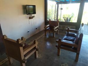 a living room with chairs and a tv on a wall at Recanto Cravo e Canela in Itatiaia